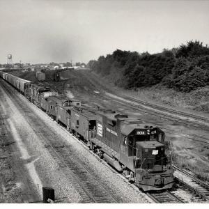 Photograph of GP38-2 8014, numerous cabooses and a westbound grain train at Orrville OH. 7/30/76