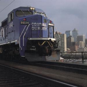 Wood Laminated Promotional photo: Philadelphia, Conrail's headquarters city, forms the backdrop for a GE C40-8 wide-cab locomotive on the 'high line,' just west of the downtown area.