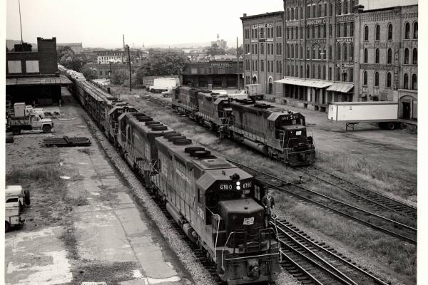 Photograph of SD45 6180, an unknown SD45 and GP38-2 8127 leading train JM-4 at Binghamton NY. SD45 8112, GP38 7956 and an unknown U23B are shown in the background. 9/26/76