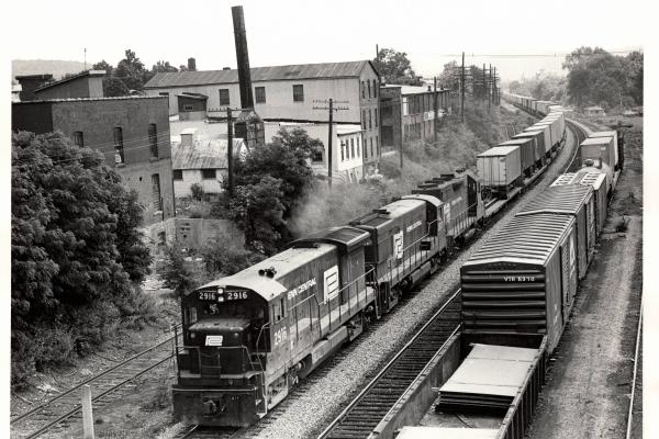Photograph of U33B 2916, an unknown U30B and a GP35 westbound on TV79 at Waverly NY. 7/3/76