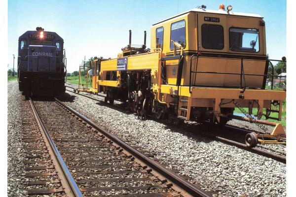 Promotional photo: An SD40-2 passes a continuous action tamper (CAT), used for compacting ballast under railroad ties. Conrail was the first U.S. railroad to use CAT equipment, which increases maintenance productivity.