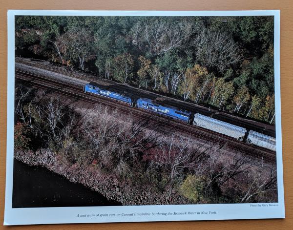 Promotional photo: A unit train of grain cars on Conrail's mainline bordering the Mohawk River in New York.