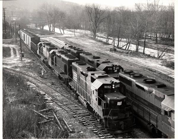 Photograph of GP38-2 8092, GP35 2579, GP38-2 8118 and other units as train JB3 passes train BJ4 at the west end of Allentown Yard. 12/5/76