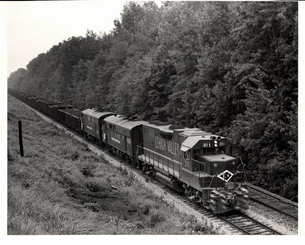Photograph of GP38AC 311, F7 1683 and another F7 on an empty ore train at Ravenna OH. 7/30/76