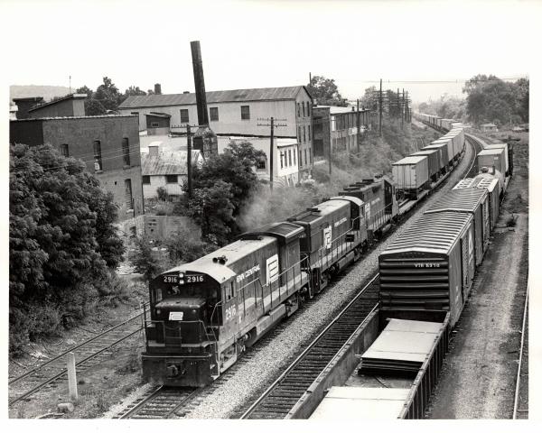 Photograph of U33B 2916, an unknown U30B and a GP35 westbound on TV79 at Waverly NY. 7/3/76