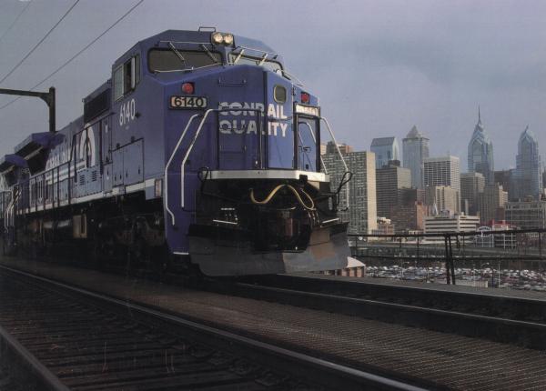 Wood Laminated Promotional photo: Philadelphia, Conrail's headquarters city, forms the backdrop for a GE C40-8 wide-cab locomotive on the 'high line,' just west of the downtown area.