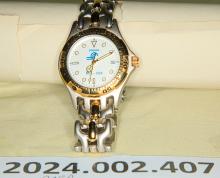 Watch (Analog) - Commemorative CR logo and 1976 - 1998 in blue on a white face. Brushed grey metal with gold colored trim; brand unknown